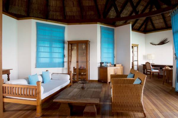 Innenbereich des Coco Palm Dhuni Kolhu Hotels mit Holzmöbeln und blauen Kissen.
