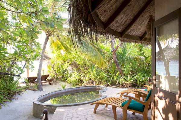 Terrasse des Coco Palm Dhuni Kolhu Hotels mit Blick auf einen Pool und die Umgebung.