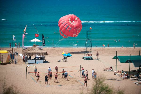 Strandszene mit Parasailing und Volleyballspiel, am Side Star Resort