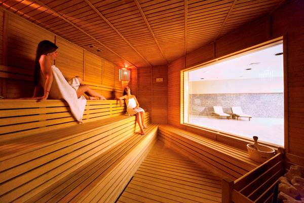 Innenansicht der Sauna im Side Star Resort mit zwei Frauen auf Holzbänken