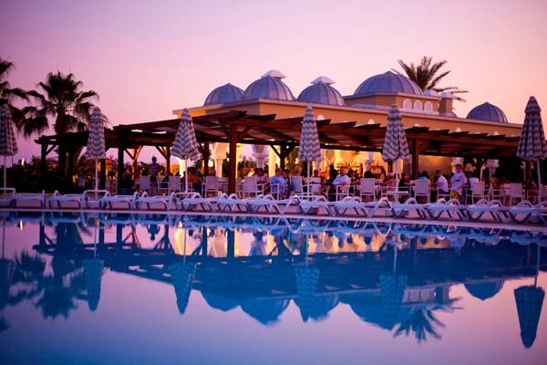 Pool des Side Star Resorts bei Sonnenuntergang mit Gästen und Palmen