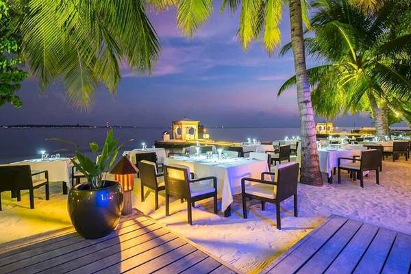 Abendessen am Strand im Lily Beach Resort & Spa mit beleuchteten Tischen und Stühlen auf weißem Tischdecken.