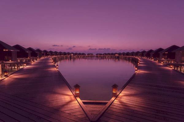 Wasservilla des Lily Beach Resort & Spa bei Nacht mit Beleuchtung und Wasserreflexion