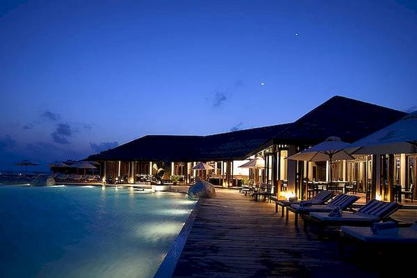 Außenansicht des Lily Beach Resort & Spa bei Nacht mit Pool, Lounge-Liegen und geöffnetem Restaurant.