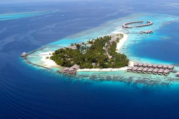 Luftaufnahme von Coco Bodu Hithi Insel mit Wasserbungalows und blauem Ozean.