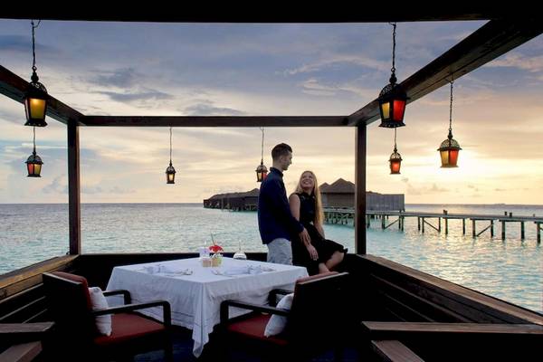 Paar auf dem Balkon des Lily Beach Resort & Spa mit Blick auf das Meer und Inseln.