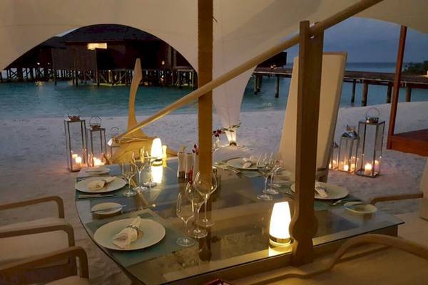 Ein Tisch auf dem Strand des Lily Beach Resort & Spa für ein Abendessen mit Kerzen und Gläsern.