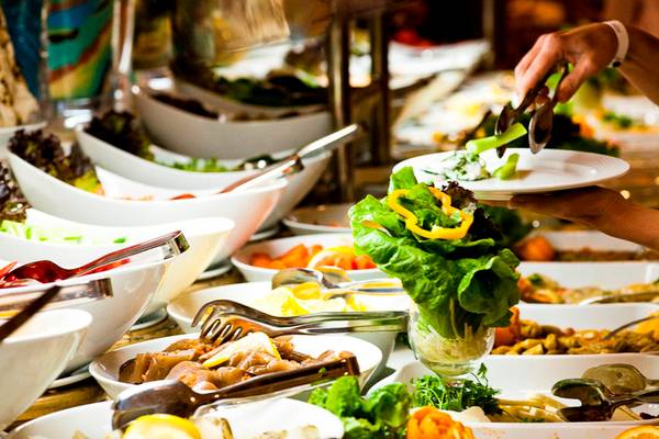 Ein Buffet mit verschiedenen Salaten und Gemüsen, serviert in weißen Schüsseln.