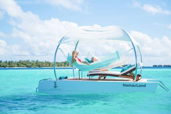 Zwei Frauen entspannen in einer Hängematte auf der HamaLand im Meer neben dem Lily Beach Resort & Spa.