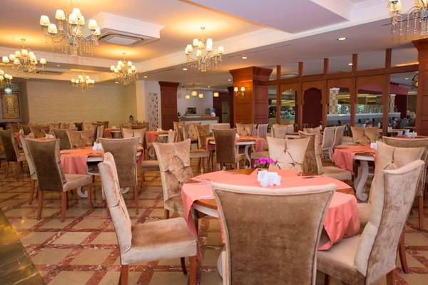Innenansicht des Restaurants im Side Star Resort mit gedeckten Tischen und Stühlen, Kronleuchtern und Marmorboden.