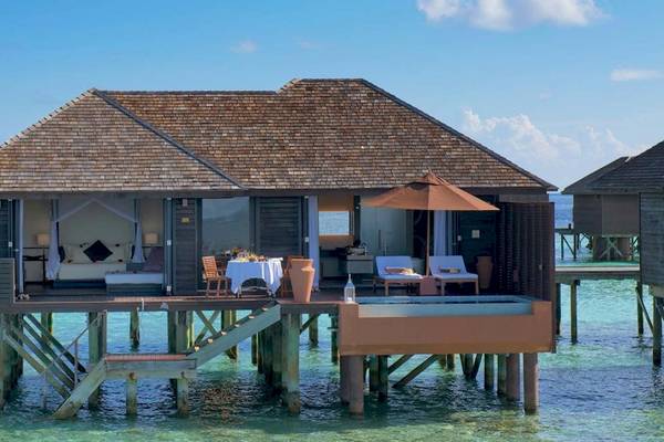 Wasservilla im Lily Beach Resort & Spa mit Blick auf das Meer und Sonnenschirm auf der Terrasse.