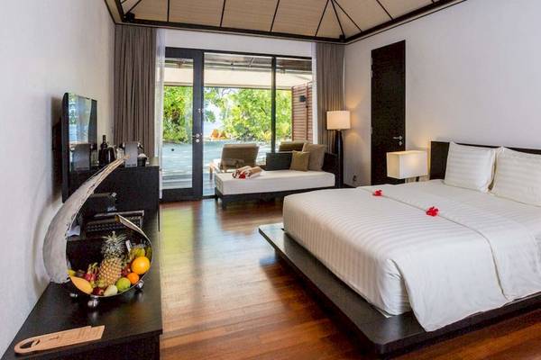 Schlafzimmer im Lily Beach Resort & Spa mit Doppelbett, Früchtekorb und Fernseher.