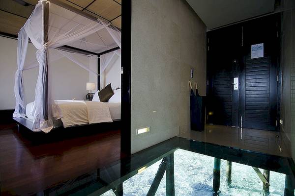 Bett mit Baldachin und Glasboden im Lily Beach Resort & Spa