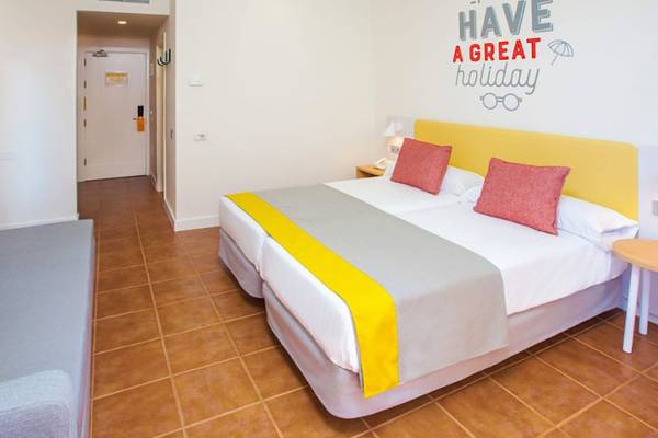 Innenansicht eines Zimmers im Abora Interclub Atlantic Hotel mit Doppelbett, gelbem Kopfteil und Wandsticker.