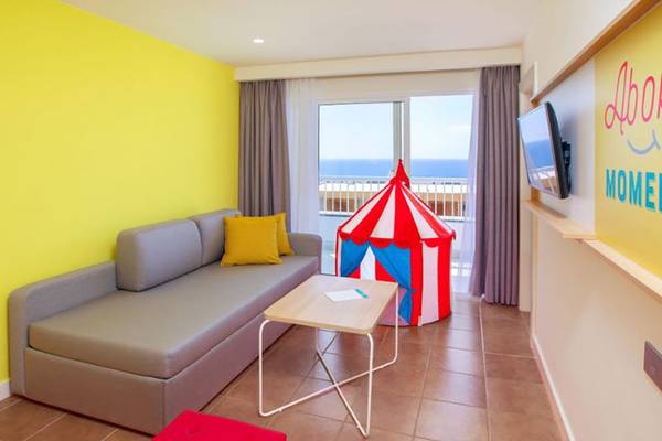 Suite Wohnbereich im Abora Interclub Atlantic Hotel mit Sofa, Tisch, rotem Hocker und Zirkuszelt.