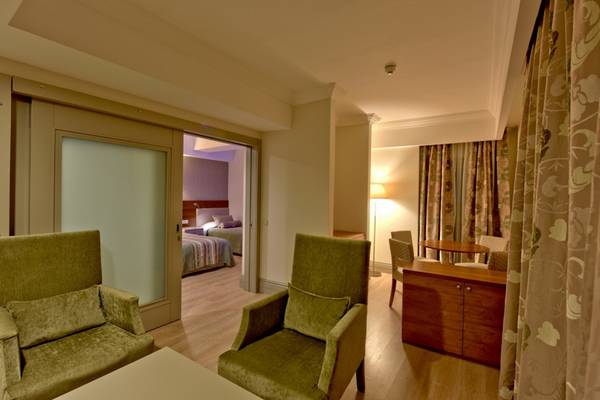 Innenansicht einer Hotelsuite im Side Star Resort mit zwei grünen Sesseln, Tisch, Sessel und Schlafzimmer