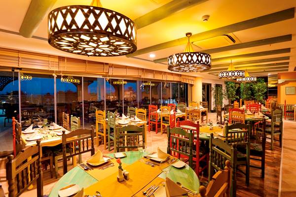Innenbereich des Side Star Resort Restaurants mit bunten Tischen und Stühlen, großen Fenstern und dekorativen Kronleuchtern.