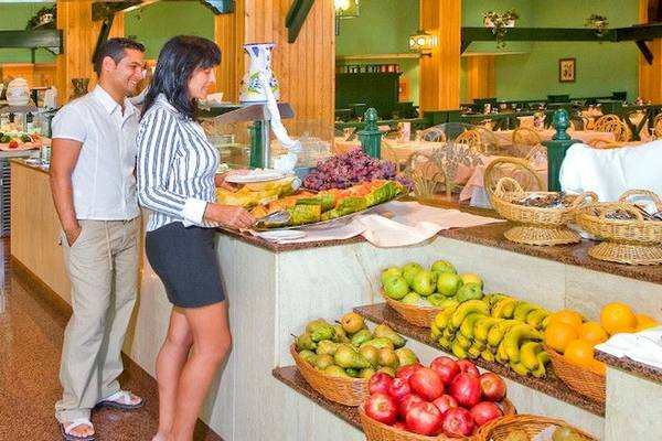 Ein Paar im Bluesea Costa Bastian Hotel Restaurant, das ein Buffet betrachtet.