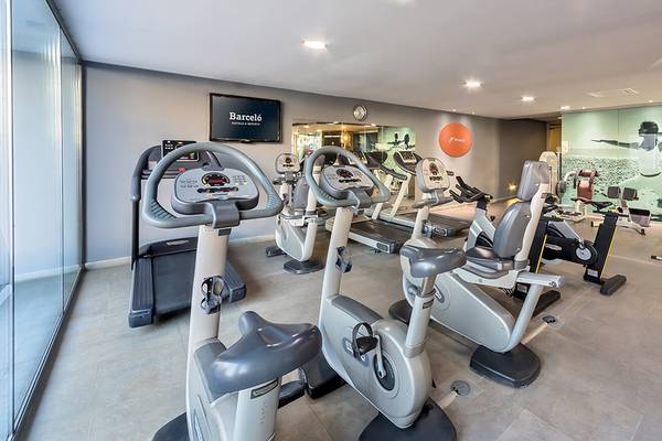 Fitnessbereich im Barcelo Santiago Hotel mit modernen Trainingsgeräten und einer großen Wandgrafik.