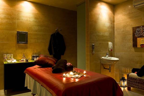 Spa-Behandlungsraum im Barcelo Santiago Hotel mit Bett, Kerzen und Handtüchern.