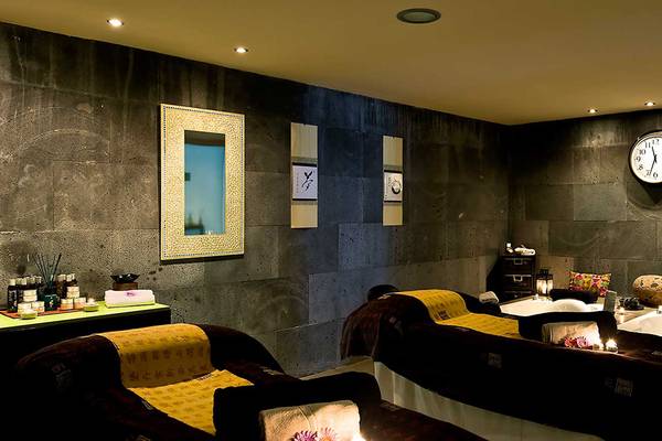 Spa-Behandlungsraum im Barcelo Santiago Hotel mit zwei Behandlungsbetten, Steinwänden und einer Uhr an der Wand.