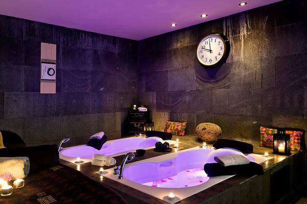 Spa-Badezimmer im Barcelo Santiago Hotel mit zwei Whirlpools, Kerzen und einer Uhr an der Wand.