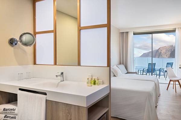 Zimmer im Barcelo Santiago Hotel mit Meerblick, inklusive Badezimmer und Schlafzimmer mit Betten, Balkon und Möbeln.