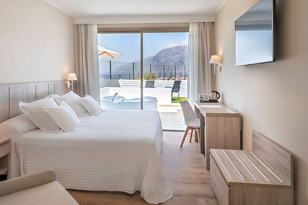 Hotelzimmer mit einem großen Bett und einer Badewanne mit Aussicht auf das Meer