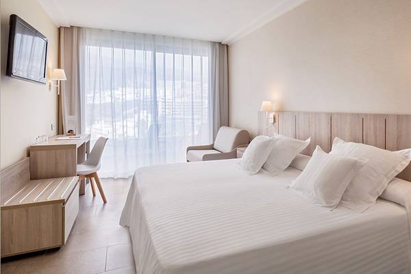 Ein modernes Hotelzimmer im Barcelo Santiago mit Bett, Schreibtisch und Blick auf die Stadt.