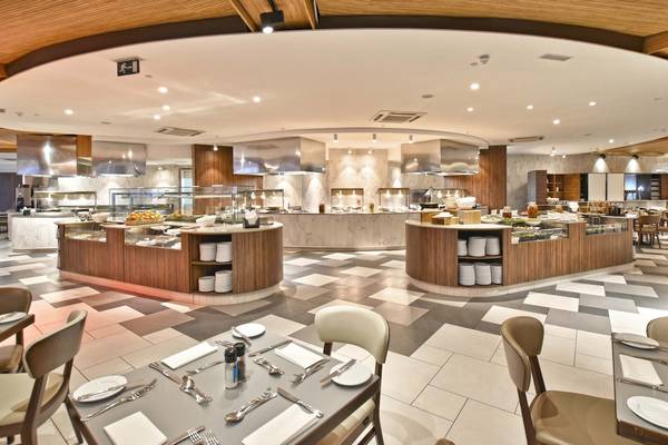Innenansicht des Restaurants im Doubletree by Hilton Malta mit Rundtheke, Buffets und gedeckten Tischen.