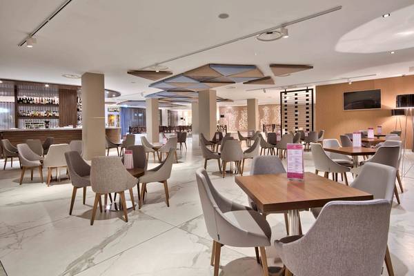 Innenbereich des Doubletree by Hilton Malta Hotel mit vielen Tischen und Stühlen.