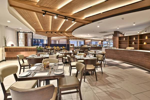 Innenraum des Restaurants im Doubletree by Hilton Malta mit modernen Holzmöbeln und gefliesten Böden.