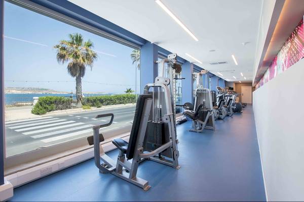 Innenansicht des Fitnesscenters im Doubletree by Hilton Malta mit Blick auf die Straße und das Meer.