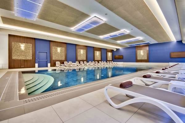 Innenpool im Doubletree by Hilton Malta mit blauen Wänden und weißen Liegestühlen