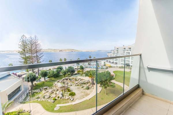 Aussicht vom Balkon des Doubletree by Hilton Malta auf das Meer und eine gepflegte Gartenanlage.