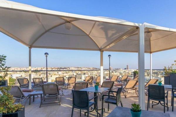 Dachterrasse des AX The Victoria Hotels mit vielen Stühlen und Tischen unter weißen Sonnenschirmen.