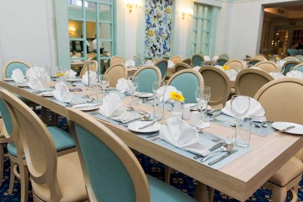 Ein elegantes Esszimmer des AX The Victoria Hotels mit gedeckten Tischen und Stühlen, gelben Blumen und blauen Kissen.