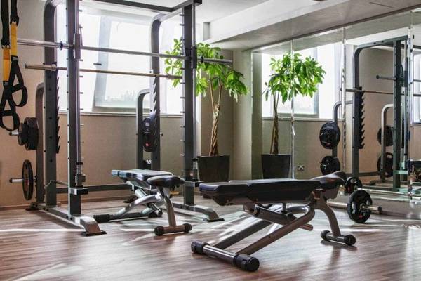 Fitnesscenter im AX The Victoria Hotel mit verschiedenen Trainingsgeräten und großen Fenstern.