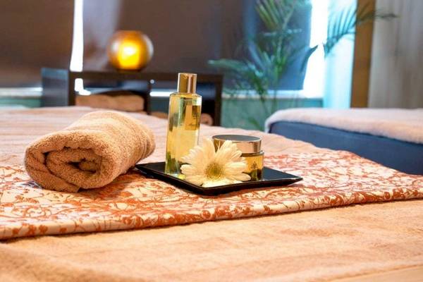 Spa-Behandlungsbereich im AX The Victoria Hotel mit einem Bett, Handtüchern, Blumen und Pflegeprodukten.