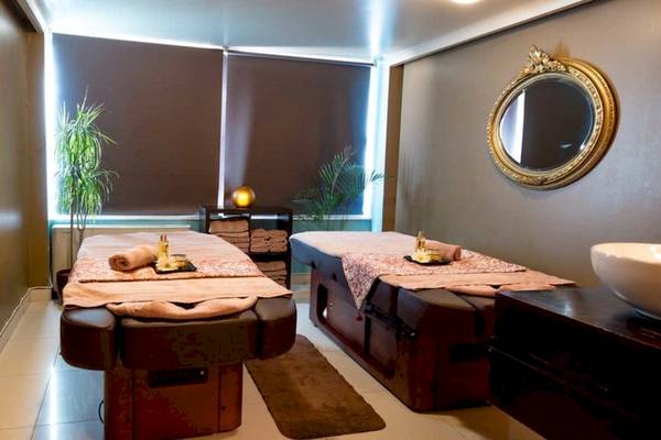 Behandlungsraum im AX The Victoria Spa mit zwei Massagetischen, Spiegel und Pflanzen.