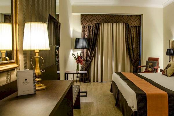 Hotelzimmer im AX The Victoria mit Bett, Lampen und Dekor.