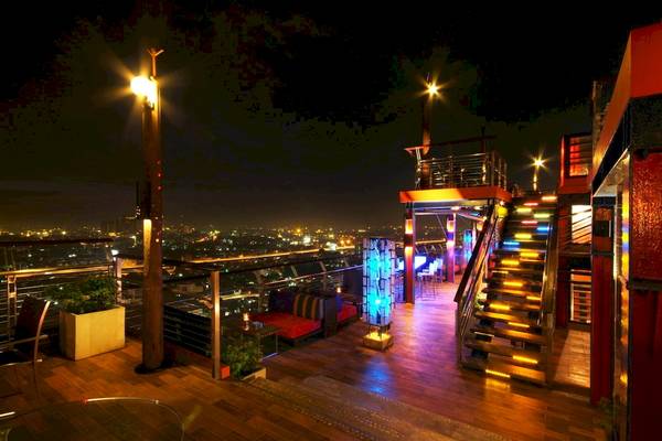Nachtansicht der Terrasse des Siam@Siam Design Hotels in Bangkok mit beleuchteten Stufen und Blick auf die Stadt.