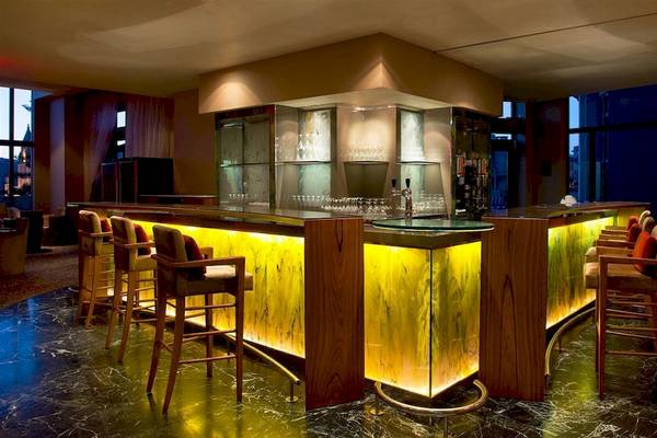 Die Bar im Malta Marriott Hotel mit gelben Beleuchtung und Holzstühlen.