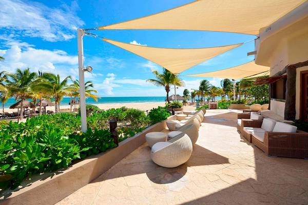 Terrasse des Catalonia Playa Maroma Hotels mit weißen Sesseln und Sonnenschirmen.