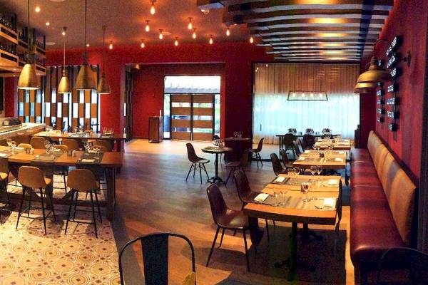 Innenansicht des Restaurants Catalonia Playa Maroma mit roten Wänden, Holzböden und modernen Möbeln.