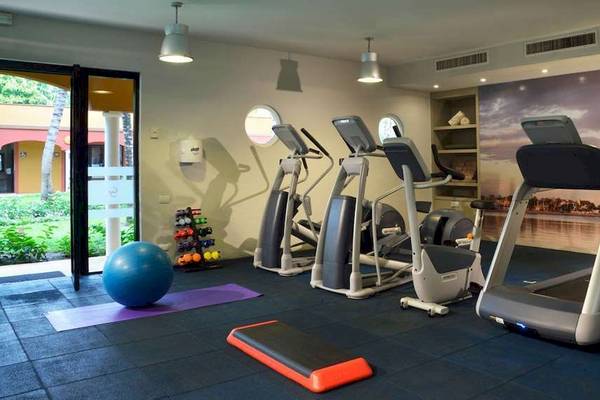 Fitnessraum im Catalonia Playa Maroma Hotel mit Laufbändern, Hanteln und einer großen Kugel.