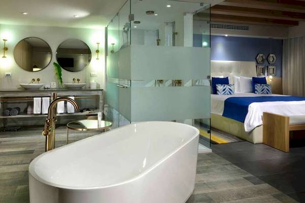 Badezimmer im Catalonia Playa Maroma Hotel mit Badewanne, Spiegelschrank und Doppelbett.