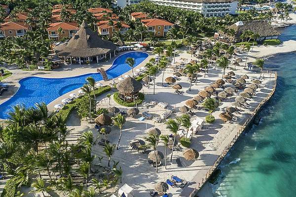 Luftaufnahme des Ocean Maya Royale Resorts mit Swimmingpool, Sonnenliegen und tropischen Palmen.
