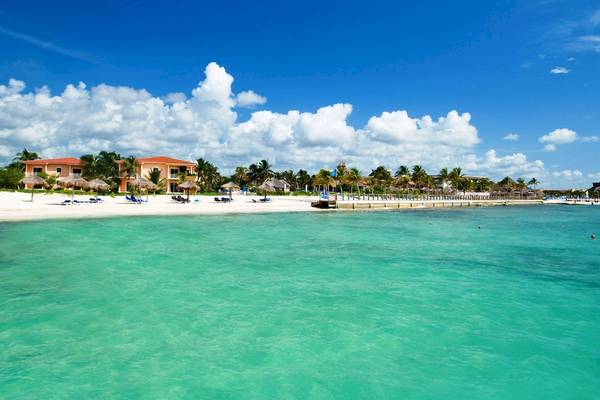 Blick auf den Strand mit weißen Palmen und blauem Wasser am Ocean Maya Royale Hotel
