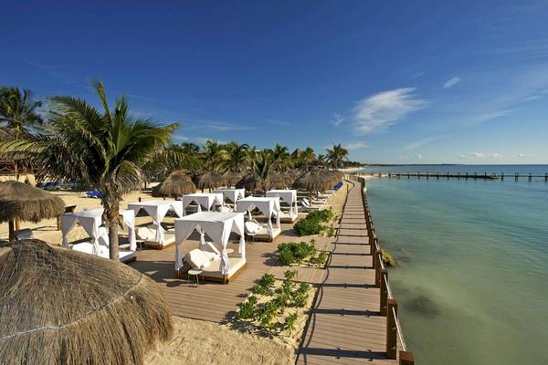 Strand des Ocean Maya Royale Hotels mit weißen Liegen und Sonnenschirmen